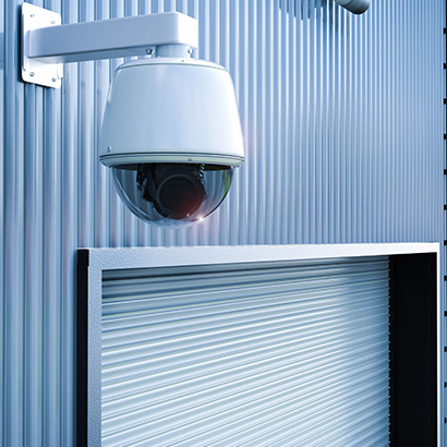 Outdoor commercial security camera mounted on a building monitoring a business entrance.